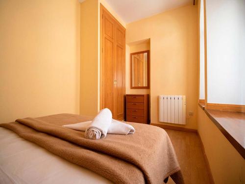 Una toalla blanca sentada en una cama en una habitación en Apartamentos Canfranc 3000, en Canfranc-Estación