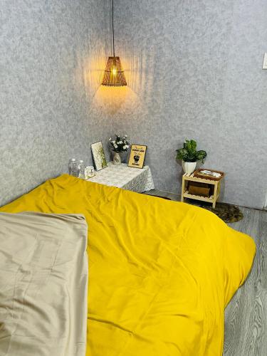 a bed with a yellow blanket in a room at Ken House 1993 in Plei Kêp