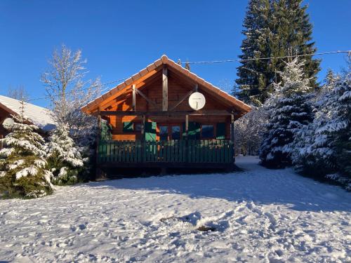 Lac des Rouges TruitesCamping-Chalets La Favière的雪地里的小木屋，树木被雪覆盖