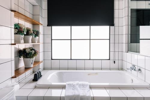 a white bathroom with a tub and a window at Beforesunset in Ban Chang Kham Luang
