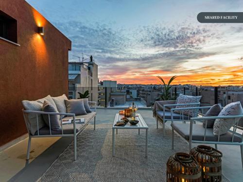 a rooftop patio with couches and a sunset at Sanders Port Piraeus in Piraeus