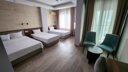 Cette chambre d'hôtel comprend deux lits, une table et des chaises. dans l'établissement Hotel Rile Men Blue, à Niš