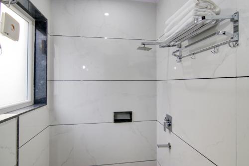 a white bathroom with white tile walls and a window at Hotel Good Will Residency - Cyber City Gurgaon in Gurgaon