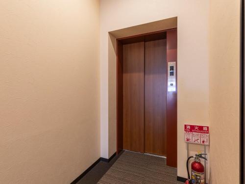 a hallway with a wooden door in a building at Tabist OSAKA PORT HOTEL L'ESPOIR in Osaka