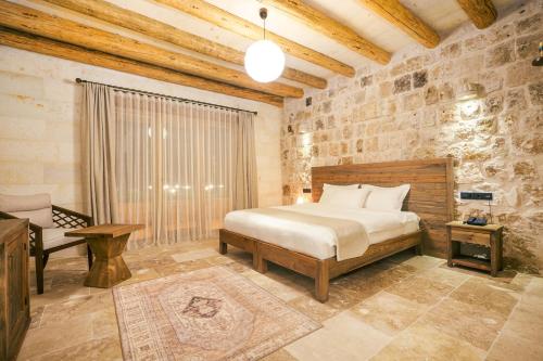 a bedroom with a bed and a chair in a room at La Fairy Cappadocia in Uçhisar