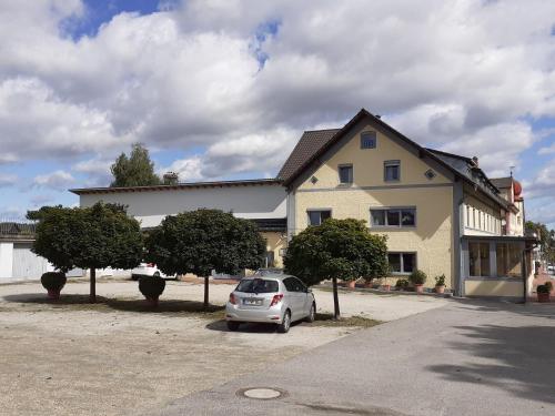 a car parked in a parking lot in front of a house at Gasthof Ramsauer in Neufahrn in Niederbayern