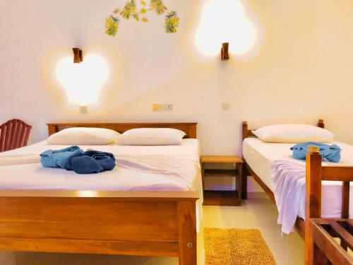 two beds in a room with two blue towels on them at Mirissa Beach Inn in Mirissa