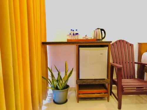 a table with a mirror and a chair and a plant at Mirissa Beach Inn in Mirissa