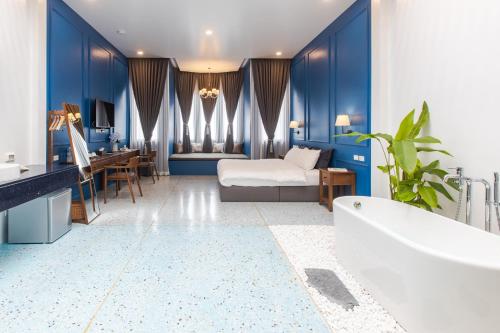 Łazienka z niebieskimi ścianami, łóżkiem i wanną w obiekcie The Elements Boutique House w Phuket