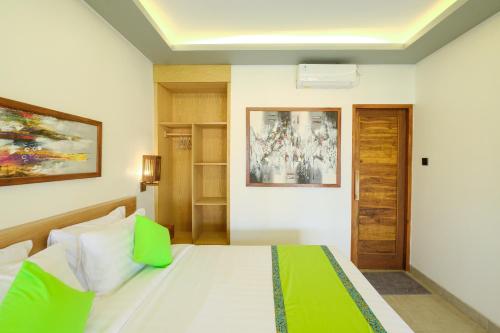 Schlafzimmer mit einem weißen Bett mit grünen Akzenten in der Unterkunft Green Bali Guest House in Munggu