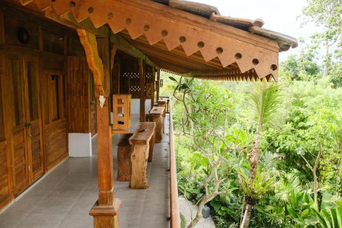 a porch of a building with benches on it at Green Bali Guest House in Munggu