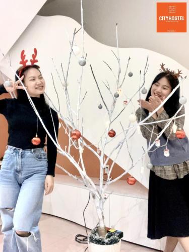 two women standing next to a christmas tree at City Hostel Da Nang in Da Nang