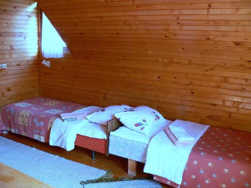 two beds in a room with wooden walls at Kivi Turismitalu in Vardi