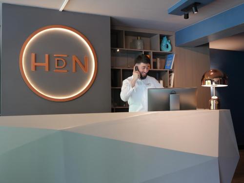 a man talking on a cell phone in front of a hin sign at Hotel du Nord Alster - auf der Uhlenhorst - SELF CHECK-IN in Hamburg