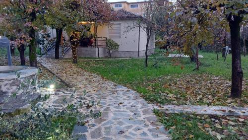 a stone path in a yard with trees and a house at Nicolaus Hidden Gem Villa in Shkodër