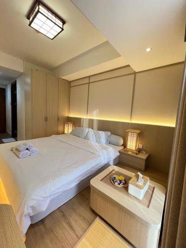 a bedroom with a large white bed and a table at Wawa Guesthouse Pollux Habibie Batam Tower A 17 in Kangboi