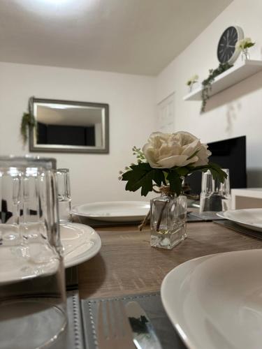 a table with white plates and a vase with a flower at Cosy Cambridge Centre Flat in Chesterton