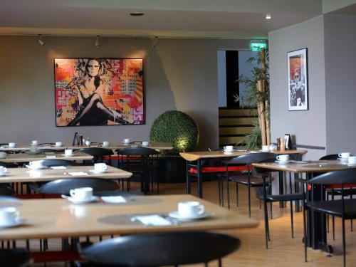 a restaurant with tables and chairs and a painting on the wall at Hotel du Nord Alster - auf der Uhlenhorst in Hamburg