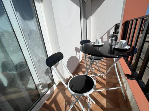 a black table and chairs on a balcony at Daisal Apartment - 2 bedroom apartment with balcony near the beach & city center, perfect for nomads, travellers, families, watersports! in Santa Maria