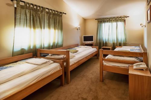 a room with three beds and a television at Apartments & Rooms - Konak Vukasinovic in Belgrade