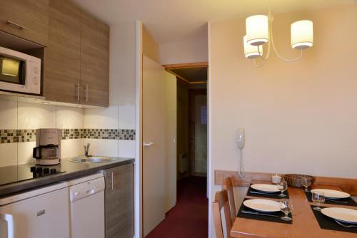 une cuisine avec une table en bois et des plaques de cuisson. dans l'établissement Appartement avec vue et accès skis aux pieds., à La Plagne Tarentaise