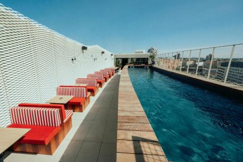 einen Pool auf dem Dach eines Gebäudes mit roten Stühlen in der Unterkunft JOST Auberge de jeunesse Montpellier Centre St Roch in Montpellier