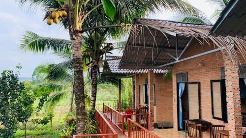 a house with a palm tree next to a porch at Gibbon Singing Home Stay in Quan Tom