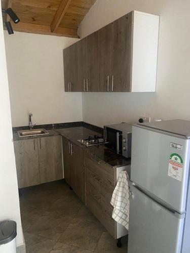 uma cozinha com um frigorífico branco e armários de madeira em Coral Villas Cottage em Ukunda