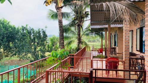 a balcony of a house with a palm tree at Gibbon Singing Home Stay in Quan Tom