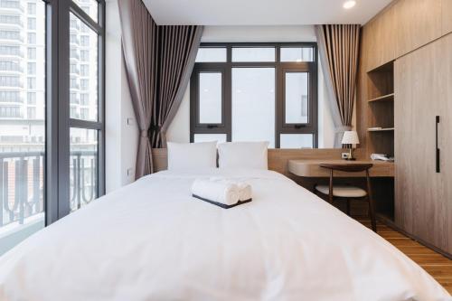a bedroom with a large white bed and a desk at Westlake Emerald Suites in Hanoi