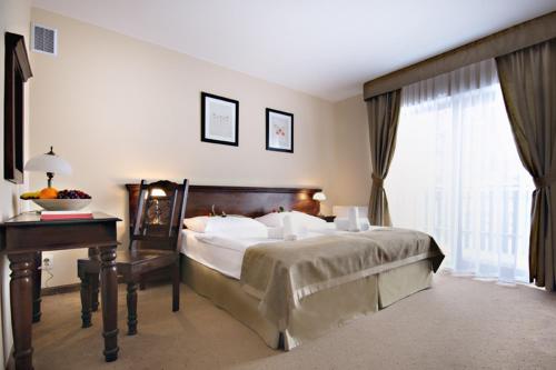 a bedroom with a bed and a desk and a window at Hotel Carmen in Karpacz