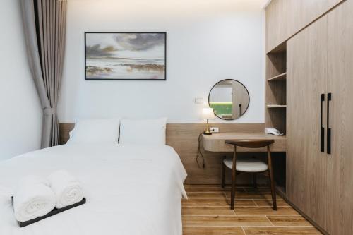 a bedroom with a bed and a desk and a mirror at Westlake Emerald Suites in Hanoi