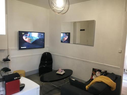 a living room with a couch and a tv on the wall at appartement T2 porte de Pantin Métro Hoche in Le Pré-Saint-Gervais