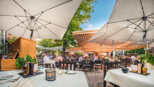 an outdoor restaurant with tables and umbrellas at Hotel Schindlerhof in Nürnberg