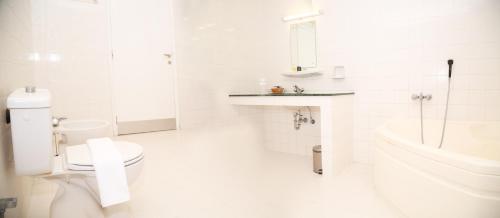 a white bathroom with a toilet and a sink at Ibri Oasis Hotel in ‘Ibrī