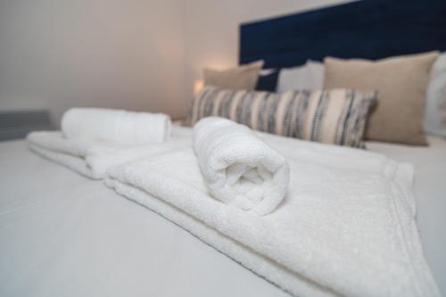 a pile of white towels sitting on a bed at VICHY - The Thornhill City Center Apartment in Wakefield