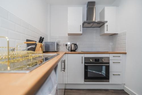 a kitchen with a sink and a stove at VICHY - The Thornhill City Center Apartment in Wakefield
