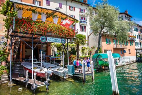 a building on a river with a boat in the water at Casa Sibylle with Sauna and Pool - Happy Rentals in Riva San Vitale