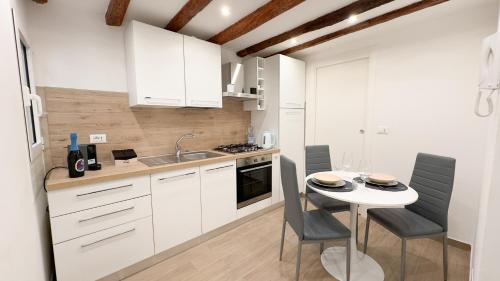 a kitchen with white cabinets and a table with chairs at Maison Studio 2 by Ca-Sa Check in Chioggia