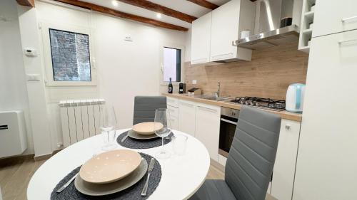 a white kitchen with a white table and chairs at Maison Studio 2 by Ca-Sa Check in Chioggia