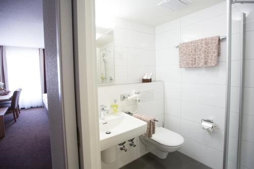 a white bathroom with a toilet and a sink at Hotel & Restaurant Rose in Bietigheim-Bissingen