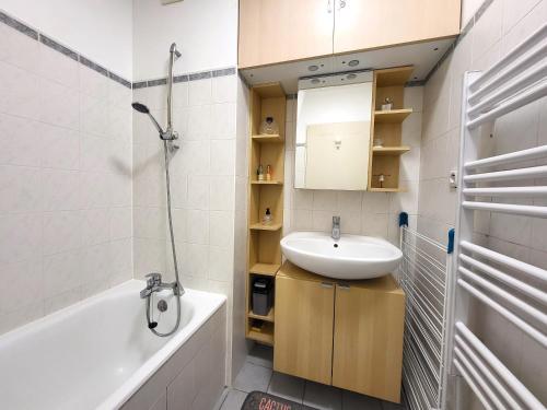 ein Badezimmer mit einem Waschbecken, einer Badewanne und einem Spiegel in der Unterkunft La Perla : F2 sans vis-à-vis, au pied du RER B in Gif-sur-Yvette