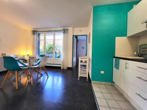 une cuisine avec des murs verts et une table et des chaises dans l'établissement La Perla : F2 sans vis-à-vis, au pied du RER B, à Gif-sur-Yvette