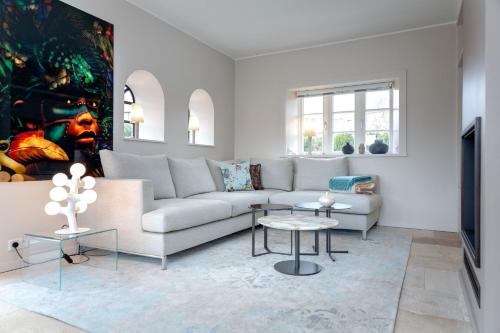 Sala de estar blanca con sofá y mesas en Ferienhaus Heidehüs Mellhörn en List