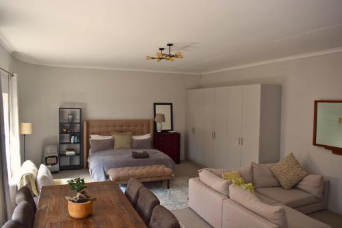 uma sala de estar com uma cama e um sofá em Riverclub Guest Suites in Riverclub, Sandton em Joanesburgo