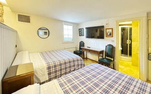 a hotel room with two beds and a desk at Posada Villa Rosa in Reinosa