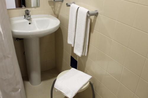 a bathroom with a sink and a toilet and towels at Hotel Gameiro in Entroncamento