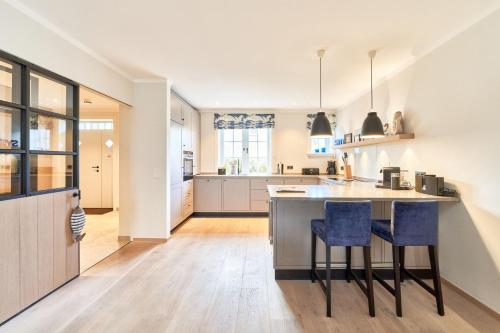 una cocina con una isla con 2 taburetes de barra azul en Ferienhaus Silbermöwe 7b en List