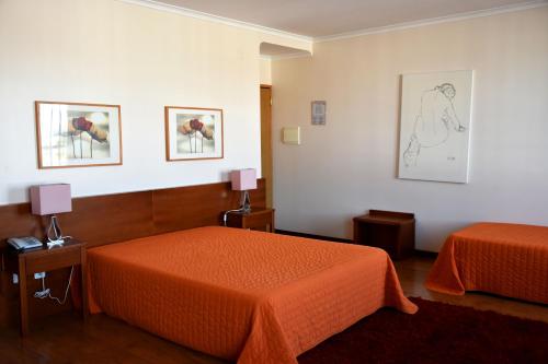 a hotel room with two beds and two lamps at Hotel Gameiro in Entroncamento