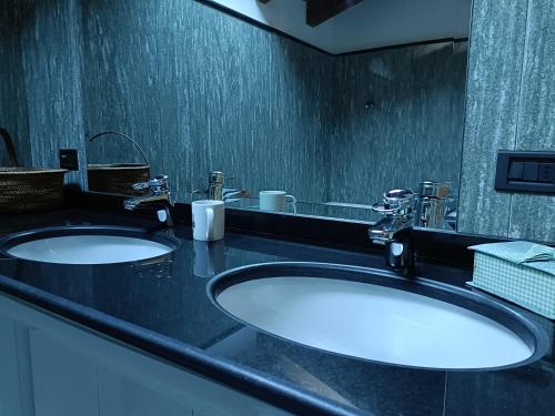 uma casa de banho com 2 lavatórios e um espelho em La dzenta méizón em Villeneuve